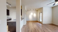 Located at 21 Gramercy Park Dr in Bryan, TX, this one-bedroom, one-bathroom unit offers a well-designed single-floor layout that maximizes its comfortable footprint. The open-concept living area flows naturally into the kitchen, which features a peninsula with granite-style countertops, rich dark wood cabinetry, stainless steel appliances including a refrigerator, electric range, and built-in microwave, all set above warm wood-look flooring. The living area is accented with built-in shelving and track lighting, with a glass door providing access to the exterior. The generously sized bedroom is carpeted for comfort, benefits from multiple windows that invite abundant natural light, and includes a ceiling fan. A spacious walk-in closet with wire shelving provides ample storage. The full bathroom is equipped with a tub-shower combo, a curved curtain rod, and dark wood cabinetry overhead, complemented by wood-look flooring. Neutral warm tones throughout the unit create a cohesive and inviting atmosphere, making this a practical and comfortable living space.