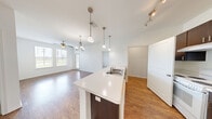This 2-bedroom, 2-bathroom single-floor residence offers a functional and well-designed layout that makes efficient use of its space. The open-concept living and kitchen area serves as the heart of the home, featuring warm hardwood-style flooring, a ceiling fan with light fixture, and large windows that invite abundant natural light. A central kitchen island with a stainless steel sink and light countertops anchors the space, complemented by dark espresso cabinetry, a white electric range, and track lighting overhead — pendant lights add a stylish touch above the island.

Both bedrooms are carpeted and bright, with windows offering outdoor views and ample room for furnishings. The primary bedroom provides a comfortable retreat with dedicated closet space. The two bathrooms maintain a consistent design aesthetic, featuring dark wood vanity cabinetry, white countertops, and wood-style flooring. One bathroom includes a tiled shower-tub combination, while the second offers a more streamlined layout with a vanity, overhead storage cabinet, and walk-in shower access. Additional conveniences include a dedicated laundry area and a closet, rounding out this practical and cohesive living space.