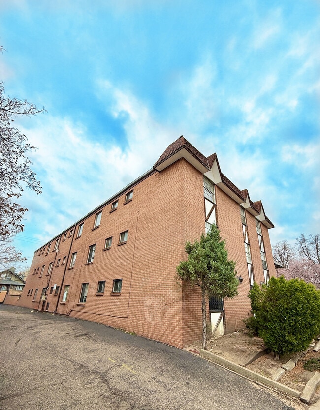 Charming brick apartment building with unique architectural features against a vibrant blue sky. - Washington Plaza