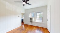 Located in Portland's vibrant NW neighborhood, this efficiently designed single-floor studio offers a thoughtful layout comprising a living room, kitchen, bathroom, and hallway. Rich, warm-toned hardwood floors run throughout the entire space, lending a timeless character that ties each room together seamlessly.

The living room is bright and airy, benefiting from a pair of double-hung windows that invite natural light and street views. A ceiling fan overhead provides year-round comfort, while vertical shiplap-style wall paneling adds a charming architectural detail.

The kitchen is a standout, featuring two-tone cabinetry with deep navy lower cabinets and crisp white uppers, paired with a matte black faucet over a single-basin sink and a stainless steel refrigerator. Clean white countertops complete the polished, updated look.

The bathroom is a true highlight, showcasing a striking green clawfoot soaking tub fitted with an overhead shower ring — a classic and elegant centerpiece. A pedestal-style vanity with a black sink rounds out the vintage-inspired aesthetic.

A connecting hallway ties the rooms together, maintaining a clean, uncluttered flow throughout. The overall ambiance blends historic charm with modern touches, making this space a distinctive and characterful Portland residence.