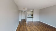 Located at 721 Due West Ave N in Nashville, Tennessee, this single-floor residence offers a clean, functional layout with a cohesive design aesthetic throughout. Rich, dark hardwood-style flooring runs continuously across the main living areas, creating a warm and grounded feel that contrasts nicely with the light gray walls and crisp white trim.

The open living area is generously proportioned and connects directly to the kitchen via a convenient pass-through counter, making the space feel open and well-integrated. The kitchen is equipped with white cabinetry, dark speckled countertops, and a white electric range with overhead ventilation, providing a practical and tidy cooking environment.

The bedrooms are well-sized, with one featuring a sliding-door closet with a built-in clothes rail and another offering a glass-paneled door that floods the room with natural light and provides views of the surrounding greenery outside. Additional windows in the secondary bedroom further enhance the sense of openness and airiness.

The bathroom includes a white vanity with dark countertops, a wall-mounted mirror, and a Hollywood-style light bar, maintaining the consistent color palette found throughout the unit. A hallway connects the main living spaces to the private areas, offering a clear and practical flow. Overall, this space presents a straightforward, move-in ready layout in a convenient Nashville location.