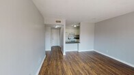 Located at 721 Due West Ave N in Nashville, Tennessee, this single-floor residence offers a clean, functional layout with a cohesive design aesthetic throughout. Rich, dark hardwood-style flooring runs continuously across the main living areas, creating a warm and grounded feel that contrasts nicely with the light gray walls and crisp white trim.

The open living area is generously proportioned and connects directly to the kitchen via a convenient pass-through counter, making the space feel open and well-integrated. The kitchen is equipped with white cabinetry, dark speckled countertops, and a white electric range with overhead ventilation, providing a practical and tidy cooking environment.

The bedrooms are well-sized, with one featuring a sliding-door closet with a built-in clothes rail and another offering a glass-paneled door that floods the room with natural light and provides views of the surrounding greenery outside. Additional windows in the secondary bedroom further enhance the sense of openness and airiness.

The bathroom includes a white vanity with dark countertops, a wall-mounted mirror, and a Hollywood-style light bar, maintaining the consistent color palette found throughout the unit. A hallway connects the main living spaces to the private areas, offering a clear and practical flow. Overall, this space presents a straightforward, move-in ready layout in a convenient Nashville location.