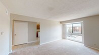 This single-floor residence offers a thoughtfully organized layout that balances comfort and functionality. The spacious living area is finished with plush carpeting and features large windows that invite an abundance of natural light while offering views of the surrounding exterior. A private entry door opens directly into this welcoming space, creating a seamless flow throughout the unit. The kitchen is well-equipped with warm wood cabinetry, granite-look countertops, and white appliances including a gas range, dishwasher, and refrigerator, all set atop easy-care tile flooring. The bedrooms are generously proportioned, each carpeted and outfitted with ceiling fans and windows fitted with blinds for light control and privacy. The layout, as seen in the overhead floor plan view, reveals a logical flow between the living, kitchen, and sleeping areas. The full bathroom features classic white tile surrounding a full-size soaking tub and shower combination, complemented by a dark-toned vanity with a mirror and built-in shelving for added storage. Textured ceilings are found throughout, contributing to the home's consistent, understated aesthetic. Overall, this residence presents a clean, neutral palette ready for personalization.