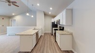 Located in the charming village of Sister Bay, WI, this single-floor residence offers a clean, modern aesthetic with a neutral color palette and consistent finishes throughout. The open-concept kitchen is a standout feature, boasting white shaker-style cabinetry, light granite countertops, stainless steel appliances, and elegant pendant lighting suspended from vaulted ceilings. A peninsula with a built-in sink seamlessly connects the kitchen to the adjoining living area, which is finished with durable wood-look flooring. The bedrooms are carpeted for comfort and warmth, each featuring ceiling fans, closet storage, and baseboard heating. One bedroom includes a convenient walk-in or reach-in closet and offers access to additional hallway space. The unit includes two well-appointed bathrooms: one with a tub-shower combination and the other with a walk-in shower stall. Both bathrooms feature white cabinetry with over-toilet storage, granite-topped vanities, wood-look flooring, and brushed nickel fixtures. Recessed lighting and large mirrors enhance the brightness in these spaces. Overall, the residence presents a cohesive, move-in-ready interior with contemporary finishes suited for comfortable year-round living in Door County.