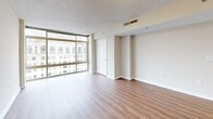 This studio unit on the 15th floor of a high-rise building in Silver Spring, Maryland offers a compact and functional layout across a single level. The open-plan living and kitchen area is anchored by light hardwood-style flooring and floor-to-ceiling windows that flood the space with natural light and frame expansive views of the surrounding Silver Spring skyline.

The kitchen is well-equipped, featuring warm honey-toned cabinetry with ample upper and lower storage, dark granite-style countertops, and a full suite of black appliances including a gas range, built-in microwave, dishwasher, and a stainless steel refrigerator. A recessed ceiling light fixture brightens the workspace, and light tile flooring completes the kitchen aesthetic.

The living area is generously proportioned for a studio layout, with clean neutral walls, a textured ceiling, and continuous hardwood-style flooring. Large windows along one wall provide abundant natural light and sweeping urban views, creating an airy atmosphere.

The bathroom features white tile flooring and walls, a full tub and shower, a wide vanity countertop with an extended mirror, warm wood cabinetry below, and a multi-bulb light fixture overhead. A dedicated closet provides additional storage. A bright, neutral hallway connects the rooms, completing this efficient and well-appointed urban residence.