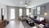 This single-floor residence showcases a thoughtfully designed interior that balances modern aesthetics with comfortable living. The living room serves as a focal point, featuring light wood-look flooring, neutral gray walls, and a ceiling fan. Large windows with patterned drapery fill the space with natural light, while a private door provides outdoor access. A curated gallery wall with framed artwork and decorative floral accents adds visual interest.

The kitchen is equipped with stainless steel appliances, including a range, microwave, and French door refrigerator. Dark lower cabinetry contrasts with high-gloss white upper cabinets and a neutral tile backsplash. A peninsula with an integrated sink and pendant lighting overhead offers casual bar seating, making it ideal for both cooking and entertaining.

The bedroom features plush carpeting, dual windows with natural light, a ceiling fan, and a dramatic dark accent wall that creates a bold, intimate atmosphere. The bathroom includes a soaking tub and shower combination, dark wood vanity cabinetry, and clean white tile. A dedicated laundry room with a full-size washer and dryer adds everyday convenience, completing this well-appointed residence.