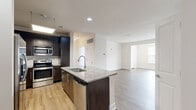 This thoughtfully designed 2-bedroom, 2-bathroom residence offers a comfortable and modern living experience across a single floor. The open-concept layout seamlessly connects the kitchen, dining, and living areas, creating a bright and airy atmosphere enhanced by recessed lighting and large windows that invite natural light throughout.

The kitchen is a standout feature, showcasing dark espresso cabinetry, granite countertops, stainless steel appliances, and a central island with a built-in sink — ideal for both cooking and casual entertaining. Light wood-style flooring flows through the main living areas, complementing the clean, neutral color palette.

The living room is anchored by a sleek, built-in linear fireplace with a granite surround, adding both warmth and a contemporary focal point to the space. The generously sized primary bedroom features plush carpeting and dedicated closet space with wire shelving systems for organized storage. The second bedroom, also carpeted, includes a ceiling fan and a bright window with outdoor views.

Both bathrooms are well-appointed with granite vanity tops, dark wood cabinetry, and tile flooring. One bathroom features a glass-enclosed walk-in shower. A dedicated in-unit laundry room with full-size washer and dryer hookups adds everyday convenience to this polished and functional home.