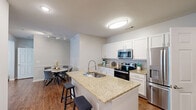 Located at 1 Flycatcher Way in Arden, NC, this thoughtfully designed single-story home offers a comfortable and functional layout across two bedrooms, two full bathrooms, and three closets. The open-concept kitchen and living area serves as the heart of the home, featuring crisp white cabinetry, granite countertops, stainless steel appliances, and a peninsula island with an undermount sink — ideal for both everyday cooking and casual dining. Rich hardwood-style flooring runs throughout, adding warmth and continuity to the space. The living room is bright and airy, benefiting from multiple windows with natural light, crown molding, ceiling fans, and recessed lighting that contribute to an inviting atmosphere. Both bedrooms are comfortably sized, each equipped with a ceiling fan and generous closet storage. The primary bedroom offers a well-proportioned retreat, while its en-suite bathroom features a double-sink granite vanity and ample cabinet storage. The second bathroom mirrors the same quality finishes, with a granite countertop vanity and hardwood-style flooring. A dedicated hallway connects the rooms efficiently, completing a practical and polished floor plan well suited for modern living in the Arden area.