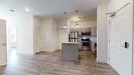 Located at 408 Northampton Rd in Amherst, Massachusetts, this single-floor residence offers a clean, contemporary design with cohesive finishes throughout. Wide-plank wood-look flooring runs continuously across the living areas, lending warmth and visual continuity to the space.

The heart of the home is an open-concept kitchen and living area, where a central island with a granite-style countertop serves as both a prep space and casual gathering point. Gray shaker-style cabinetry lines the walls, complemented by a herringbone tile backsplash and a full suite of stainless steel appliances, including a refrigerator, range, and built-in microwave. Stylish pendant lights hang above the island, adding a modern touch to the well-lit kitchen.

The living area flows naturally from the kitchen, creating an open and airy feel. A paneled entry door with a modern hardware finish provides a welcoming entrance. Additional rooms include well-proportioned bedrooms with natural light from blinds-fitted windows and ceiling fans for comfort.

The bathrooms are finished consistently with the rest of the unit, featuring wood-look flooring, granite-topped vanities, and full tub-shower combinations in clean white surrounds. The overall aesthetic throughout is fresh, neutral, and move-in ready, making this Amherst property a functional and attractive living space.