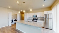 This single-floor residence at 4140 Silo View Dr in DeForest, Wisconsin offers a thoughtfully designed open-concept layout with contemporary finishes throughout. Durable wood-style flooring runs through the main living areas, while plush carpet adds comfort to the bedrooms.

The kitchen serves as the heart of the home, anchored by a large island with a granite countertop and an undermount sink illuminated by stylish pendant lighting. White shaker-style cabinetry pairs elegantly with stainless steel appliances, including a refrigerator, range, and microwave. A sliding glass door brings in natural light and connects the kitchen to the outdoors. A dedicated laundry area with a full-size washer is conveniently accessible from the kitchen space.

The bedrooms are bright and well-proportioned, each featuring windows with blinds that allow natural light to filter in, along with ceiling fans for added comfort. The bathrooms are finished with white shaker vanities, granite countertops, undermount sinks, and wood-style flooring, maintaining a consistent, clean aesthetic. A wide-format mirror above the vanity enhances the sense of space.

The entry hallway provides a welcoming transition into the home, with open shelving and neutral warm-toned walls that carry throughout, creating a cohesive and inviting atmosphere.