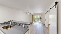 Located at 400 E Remington Dr in Sunnyvale, CA, this well-designed single-floor residence makes smart use of its compact footprint. Light hardwood flooring runs throughout, lending warmth and visual continuity to the entire space.

The open-concept kitchen and living area form the heart of the home. The kitchen is outfitted with white cabinetry, stainless steel appliances including a refrigerator, range, and microwave, a mosaic tile backsplash, and a gray-topped breakfast bar that doubles as a pass-through to the living area. The living room is bright and airy, featuring a ceiling fan, a baseboard heater, and large sliding glass doors that open to a private balcony framed by a rustic stone accent wall and lush greenery beyond.

A stylish barn-style sliding door adds a modern farmhouse touch to one of the rooms, which also benefits from direct balcony access. A dedicated closet with light wood flooring provides convenient storage. The hallway connects the living spaces to two well-appointed bathrooms, one of which features a tub-shower combination enclosed by a sleek sliding glass door, large-format tile surround with a decorative mosaic accent strip, and brushed nickel fixtures. The overall aesthetic is clean, bright, and contemporary throughout.