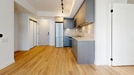Located at 75 Broadway Ave in the heart of Toronto's Midtown, this modern unit offers a thoughtfully designed open-concept layout that maximizes its well-proportioned single-floor footprint. Light-toned hardwood flooring flows seamlessly throughout the living areas, complementing the clean white walls and creating a bright, cohesive aesthetic.

The kitchen is outfitted with flat-front grey cabinetry, white quartz countertops, stainless steel appliances including a refrigerator, stove, and built-in microwave, and under-cabinet lighting that adds both function and warmth. A peninsula counter subtly delineates the kitchen from the open living area, which benefits from large floor-to-ceiling sliding glass doors that flood the space with natural light and provide views of the surrounding urban skyline.

The bedroom area is airy and well-lit, featuring a generous window that frames views of the neighbouring architecture and brings in abundant daylight. The bathroom is finished with marble-style tile flooring, a vessel sink atop a white floating vanity, a large mirrored medicine cabinet, and warm wood-toned upper cabinetry. Track lighting in the entry and recessed fixtures throughout complete the unit's polished, contemporary design. The space also includes a closet and a modern entry door with a digital lock.