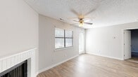 This well-appointed single-floor residence in Raleigh, NC offers a practical and comfortable layout across a thoughtfully organized floor plan. The living room serves as the heart of the home, featuring warm wood-look flooring, a classic brick-surround fireplace, a ceiling fan with light fixture, and a textured ceiling. Natural light filters in through blinds-equipped windows, and a glass-paneled door provides convenient exterior access. The kitchen is equipped with dark espresso-toned cabinetry, stainless steel appliances including a refrigerator and electric range, light countertops, and a built-in pantry closet with shelving — all complemented by the same wood-look flooring. The spacious bedroom is carpeted for comfort and features a window with natural light, a textured ceiling, and direct access to a walk-in closet outfitted with dual shelving rails. The full bathroom includes a tub-shower combination with built-in shelving and brushed nickel fixtures. Neutral gray tones throughout the home create a cohesive, move-in-ready aesthetic, while consistent flooring materials and clean white trim add a polished finish to every room.