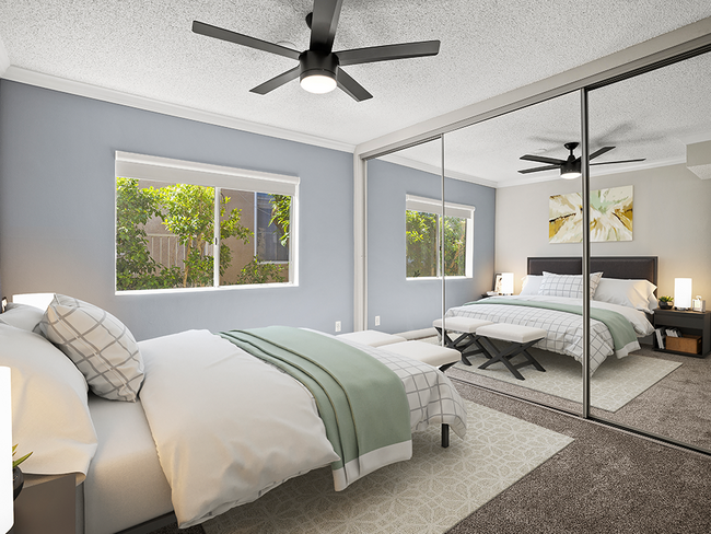 Carpeted bedroom with ceiling fan and large mirrored closets. - Tilden II Apartments