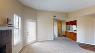 Located at 6575 Ashcroft Dr in Colorado Springs, Colorado, this single-floor residence offers a functional and comfortable layout with a warm, neutral color palette throughout. The open living area greets you upon entry, featuring soft carpeting, vaulted ceilings, and multiple windows that allow natural light to fill the space. A door provides direct access to an outdoor area, enhancing the sense of openness. The living space flows seamlessly into the kitchen, which is equipped with rich warm-toned wood cabinetry, light granite-style countertops, white appliances including a refrigerator, electric range, and over-the-range microwave, as well as wood-look flooring that adds a touch of warmth. The bedrooms are carpeted and generously sized, with one featuring a ceiling fan with light fixture and a window for natural light. The bathroom is well-appointed with a wooden vanity, granite-style countertop, a large mirror, a tub-shower combination, and wood-look flooring. Textured ceilings are present throughout the home, and the overall design reflects a classic, practical aesthetic suited for comfortable everyday living in the Colorado Springs area.