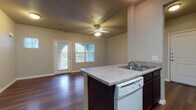Located at 1010 Locke St in San Antonio, Texas, this single-floor unit offers a well-designed layout with a cohesive, modern aesthetic throughout. Rich, dark hardwood-style flooring runs continuously across the main living areas and bedroom, providing a warm and polished foundation for the entire space.

The open living area is bright and welcoming, featuring a ceiling fan with integrated lighting and a door that leads directly to a private balcony. An arched window alongside the door allows natural light to fill the room, creating an airy atmosphere. The space flows seamlessly into the kitchen and dining area, making it well-suited for everyday living and entertaining.

The kitchen is outfitted with dark espresso cabinetry that extends to the upper walls, offering generous storage. Light-toned countertops provide contrast, and a peninsula with a built-in sink and dishwasher adds functional prep and dining space. White appliances, including a range, microwave, and refrigerator, complete the kitchen suite.

The bedroom is a quiet retreat with continued hardwood-style flooring and access to a walk-in closet with wire shelving. The bathroom features stone-look tile flooring, a dark vanity with a sink, a large mirror, and a full tub-shower combination, delivering both practicality and comfort.