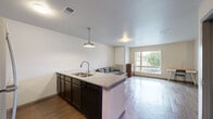 Located at 117 27th Ave SE in Minneapolis, MN, this one-bedroom, one-bathroom unit offers a well-designed, single-floor layout that maximizes functionality. The open-concept living and kitchen area serves as the heart of the unit, where wood-style flooring extends throughout and connects the spaces seamlessly. The kitchen is a standout feature, anchored by a central island with granite countertops and a built-in sink. Dark espresso cabinetry provides ample storage and contrasts elegantly with the light countertops. Stainless steel appliances, including a full-size refrigerator, electric range, and built-in microwave, complete the kitchen. A pendant light over the island adds a modern touch. The living area is bright and open, benefiting from a large window that invites natural light and provides outdoor views of the surrounding neighborhood. The spacious bedroom features the same wood-style flooring, a window for additional natural light, and enough room for a full furniture arrangement. The bathroom is clean and well-appointed, featuring a granite-topped vanity with dark cabinetry, a full tub-shower combo, and wood-look tile flooring. Throughout the unit, neutral wall tones and a textured ceiling contribute to a cohesive, modern aesthetic.