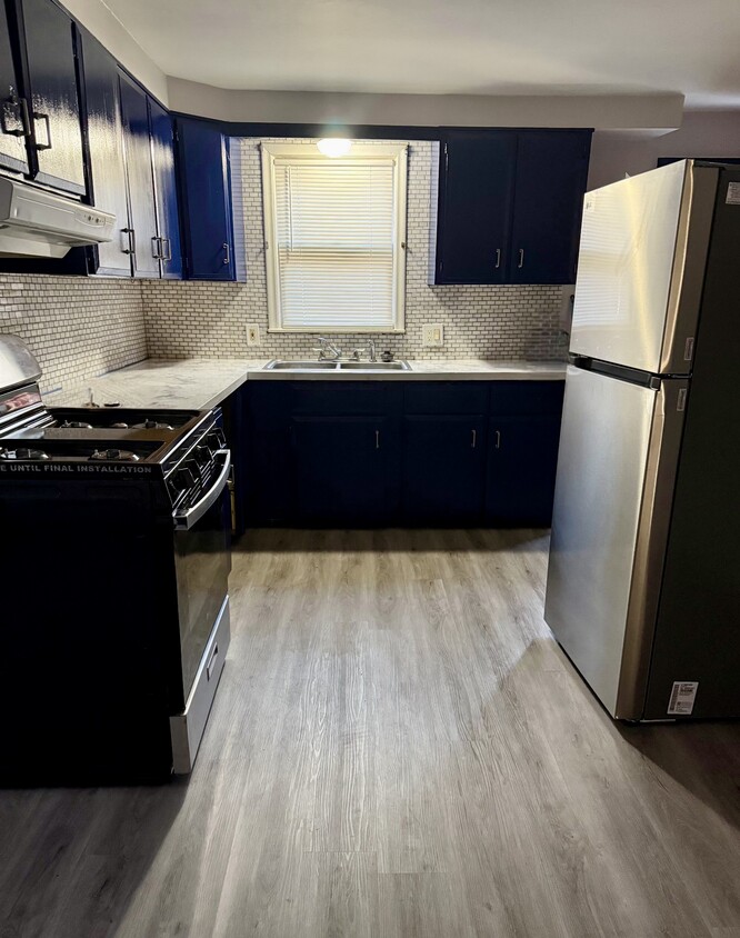 Newly renovated kitchen with blue cabinets, backsplash, and granite countertops - 20212 Mada Ave