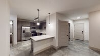 Located at 417 W Hargett St in the heart of downtown Raleigh, NC, this single-floor unit showcases a modern, urban aesthetic carried consistently throughout its spaces. Polished concrete floors run throughout the unit, lending an industrial-chic character while remaining easy to maintain.

The kitchen serves as a focal point, featuring dark wood-grain cabinetry paired with crisp white subway tile backsplash and light quartz countertops. A full suite of stainless steel appliances—including a refrigerator with ice maker, electric range, over-the-range microwave, and dishwasher—equips the space for everyday cooking. A peninsula with bar-height overhang extends toward the living area, offering additional prep space and casual seating. Pendant lighting and a track light fixture illuminate the kitchen, adding warmth to the contemporary palette.

The bedrooms are neutrally finished with smooth walls, polished concrete floors, and windows fitted with horizontal blinds that allow natural light and urban views. One bedroom includes a ceiling fan. The bathroom features a soaking tub and shower combination enclosed by full white subway tile surround, complemented by brushed nickel fixtures. A stacked washer and dryer unit is also included within the layout, adding everyday convenience to this well-appointed downtown Raleigh residence.