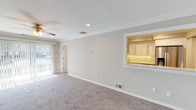 Located at 110 Westwood Drive in Westbury, NY, this unit at Jericho Townhomes presents a well-organized single-floor layout designed for comfortable everyday living. The spacious living room features plush wall-to-wall carpeting, crown molding, recessed lighting, and a ceiling fan, with large sliding glass doors that flood the space with natural light and provide outdoor views. A convenient pass-through window connects the living area directly to the kitchen, enhancing the open feel of the home. The kitchen is equipped with crisp white cabinetry, stone-look countertops, a marble-style tile backsplash, and stainless steel appliances including a gas range with over-the-range microwave. Wood-look flooring grounds the kitchen, adding a warm contrast to the bright cabinetry. The bedrooms are generously sized, each featuring soft carpeting, crown molding, ceiling fans, and windows with blinds that allow for ample natural light. The bathroom has been tastefully updated with marble-look porcelain tile wall surrounds, a glass-enclosed shower, a white vanity with stone countertop, and gold-tone fixtures, creating a clean and refined aesthetic. Throughout the unit, neutral tones and consistent finishes create a cohesive and move-in-ready environment.