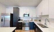 Located at 376 Penley Lake Cir in Cape Coral, Florida, this thoughtfully designed one-bedroom, one-bathroom residence offers a well-appointed layout across a single floor. The modern kitchen is a standout feature, showcasing striking two-tone cabinetry with dark lower cabinets and crisp white upper cabinets, white quartz countertops, a subway tile backsplash, stainless steel appliances, and a central island illuminated by pendant lighting — ideal for both cooking and casual dining. Wood-look flooring flows consistently throughout the home, lending warmth and cohesion to the space. The open living area is bright and inviting, benefiting from a ceiling fan, generous natural light, and sliding glass doors that lead directly to a private balcony with outdoor views. The spacious primary bedroom features large windows, a ceiling fan, and ample room for relaxation. A dedicated office provides a quiet, functional workspace with clean neutral walls and wood-look flooring. The full bathroom is cleanly finished with a dark vanity, white quartz countertop, a large mirror, and a shower-tub combination. A hallway connects the rooms efficiently, completing this well-organized and contemporary residence in Southwest Florida.