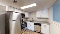Located at 7141 Bronner Cir in Louisville, KY, this single-floor residence offers a well-organized layout with a blend of modern updates and comfortable living spaces. The kitchen stands out with crisp white shaker cabinetry, granite-look countertops, and a full suite of stainless steel appliances including a refrigerator, range, microwave, and dishwasher. Light wood-style flooring and recessed panel lighting give the kitchen a clean, functional aesthetic. Adjacent to the kitchen, the dining area flows naturally into a spacious living room finished with rich, dark hardwood-style flooring. A large sliding glass door fills the living room with natural light and provides direct views of the outdoors. The dining area features a stylish pendant light fixture, creating an inviting atmosphere. The bedrooms are carpeted for comfort and finished with neutral-toned walls, textured ceilings, and windows that allow natural light to filter in. The bathroom is equipped with a full tub-and-shower combination framed by classic white tile surround. Throughout the unit, a consistent neutral color palette and clean finishes create a cohesive and move-in-ready environment.