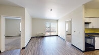 Located at 6150 W 13th Ave in Lakewood, Colorado, this single-story unit offers a well-organized layout with a variety of functional spaces. The main living area is finished with durable wood-style flooring, neutral walls, and a large sliding glass door that frames views of the surrounding Lakewood neighborhood while drawing in generous natural light. A wall-mounted HVAC unit provides climate control directly in the living space.

The U-shaped kitchen is equipped with white cabinetry, dark countertops, and a bold yellow backsplash that adds a distinct visual accent. Black appliances—including a range, dishwasher, and refrigerator—complement the design, and the wood-style flooring continues throughout.

A dedicated laundry area houses a stacked washer and dryer unit, offering added convenience. The bedroom features plush carpeting, a window with exterior views, and access to a spacious walk-in closet outfitted with wire shelving along multiple walls for ample storage.

The bathroom includes a full tub-shower combination with white tile surround, stainless steel grab bars for accessibility, a dark-countered vanity with white cabinetry, and wood-style flooring. The overall palette is clean and neutral, creating a cohesive and practical living environment throughout.