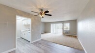 Located at 9440 Clover Avenue in Fountain Valley, CA, this single-floor, one-bedroom, one-bathroom residence offers a practical and comfortable layout. The open-concept living room is carpeted and bathed in natural light through a large sliding glass door fitted with vertical blinds, which also provides access to the outdoors. A wall-mounted air conditioning unit and a ceiling fan with a light fixture keep the space comfortable year-round. The galley-style kitchen is efficiently designed with white cabinetry, granite-look countertops, a stainless steel sink, a gas range with oven, a built-in microwave, and a dishwasher. Recessed lighting illuminates the kitchen, which transitions seamlessly to the living area via an open passageway with light wood-style flooring throughout. The bedroom offers plush carpeting, natural light from a window with vertical blinds, and ample storage with two closets. The bathroom is well-appointed with a tub and shower combination enclosed by sliding glass doors, a white vanity with granite-look countertops, and wood-style flooring. Neutral tones and clean finishes throughout give the space a bright, move-in-ready feel.