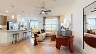 This thoughtfully designed 2-bedroom, 2-bathroom residence offers a comfortable and modern living experience across a single floor. The open-concept kitchen and living area serves as the heart of the home, featuring a large granite-topped island with an undermount sink, wood-toned cabinetry, a classic subway tile backsplash, and a full suite of stainless steel appliances including a refrigerator with ice maker, range, microwave, and dishwasher. Stylish pendant lighting illuminates the island, while light hardwood-style flooring and recessed lighting enhance the bright, airy atmosphere. The living area flows naturally from the kitchen and benefits from natural light through large windows with views of the surrounding landscape. Both bedrooms are generously proportioned, finished with plush wall-to-wall carpeting, ceiling fans, and ample natural light. The primary bedroom connects to a well-appointed en-suite bathroom featuring large-format tile flooring, a glass-enclosed shower, a vanity with dark wood cabinetry, and direct access to a spacious walk-in closet with built-in shelving and hanging rods. A second walk-in closet provides additional storage. The overall design balances clean, neutral tones with modern finishes for a polished and functional living space.