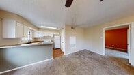 This single-floor residence offers a practical and comfortable layout designed for everyday living. The open-concept living and dining area features plush carpet flooring, neutral-toned walls, and a ceiling fan with light fixture, creating a welcoming atmosphere. Sliding glass doors lead directly to a private balcony, bringing in natural light and outdoor access.

The kitchen is efficiently designed with white cabinetry, dark hardware, a double-basin sink, electric range, and a full-size refrigerator. Wood-look flooring grounds the kitchen space, which connects seamlessly to the living area via a raised bar-height partition wall. A window above the sink provides natural light to the workspace.

The bedroom is generously sized, featuring carpet flooring, a bold accent wall, a ceiling fan, sliding glass door access to an outdoor space, and a dual-door closet offering substantial storage. An additional room with a walk-in closet provides flexible use as a second bedroom or office.

The bathroom includes a tiled tub-shower combination, a vanity with under-sink storage, a stone-look countertop, and wood-look flooring. Throughout the residence, textured ceilings and consistent neutral finishes contribute to a cohesive and functional interior aesthetic.