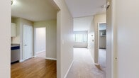 Located at 1800 Silas Deane Highway in Rocky Hill, Connecticut, this single-floor residence offers a thoughtfully designed layout with a clean, neutral aesthetic throughout. The interior is defined by warm beige and soft green tones on the walls, with a combination of wood-look flooring in key areas and plush wall-to-wall carpeting in the living and bedroom spaces.

The kitchen is a standout feature, outfitted with white shaker-style cabinetry, granite-look countertops, and a full suite of stainless steel appliances including a gas range, refrigerator, and dishwasher. The wood-look flooring here adds warmth and is easy to maintain.

The spacious living area benefits from natural light through a large window fitted with vertical blinds, and baseboard heating runs along the perimeter for efficient climate control. A wall-mounted air conditioning unit provides additional comfort.

The bedrooms are generously sized, each carpeted and featuring ample wall space. One bedroom includes a window with an outdoor view and its own wall-mounted AC unit. Closet space is accessible from the bedroom hallway.

The bathroom is neatly finished with a white vanity cabinet, a large mirror, a tub-shower combination with built-in shelving, and wood-look flooring that ties the space together cohesively.