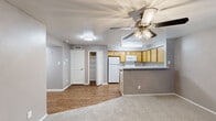 Located at 1088 Park Plaza in Austin, TX, this three-bedroom, two-bathroom unit offers a practical and well-organized single-floor layout. The open-concept living and kitchen area forms the heart of the home, where a peninsula with light granite-style countertops separates the kitchen from the living space. The kitchen is equipped with warm honey-toned cabinetry, white appliances including a refrigerator, electric range, and microwave, as well as a stainless steel sink and wood-look flooring that adds warmth underfoot. A ceiling fan with a light fixture anchors the living area, which transitions into soft carpeting throughout. The three bedrooms are each finished with neutral gray walls, carpet flooring, and ceiling fans, creating a calm and consistent atmosphere. The primary bedroom connects to one of the two bathrooms and features access to a dedicated walk-in closet outfitted with built-in shelving and hanging rods, offering generous storage. The bathrooms feature wood-toned vanities with light countertops, mirrors with overhead lighting, and a tiled shower-tub combination. A hallway connects the bedrooms and provides additional flow through the unit. The neutral color palette and consistent finishes throughout give the space a clean, move-in-ready feel.