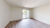 Located at 2450 Masons Ferry Dr in Herndon, VA, this 2-bedroom, 1-bathroom unit offers a practical and comfortable single-floor layout. The open living area is finished with warm wood-style flooring and neutral-toned walls, creating a clean, versatile backdrop. A hallway connects the living space seamlessly to the rest of the unit. The living room is highlighted by a sliding glass door that opens to a private balcony with outdoor views of surrounding greenery, filling the space with natural light. The galley-style kitchen features white cabinetry, light stone-look countertops, white appliances including a range, dishwasher, and refrigerator, and continues the wood-style flooring throughout. Both bedrooms are carpeted and offer a quiet, comfortable retreat. The primary bedroom includes two closets and a window with a view of the outdoors, providing ample storage and natural light. The second bedroom is similarly bright. The full bathroom is finished with wood-style flooring and includes a tub-shower combination. Throughout the unit, white six-panel doors and clean white trim provide a consistent, polished aesthetic.