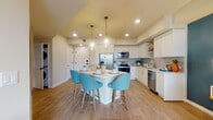 Located in Palmetto Bay, FL, this single-floor residence offers a thoughtfully designed open-concept layout that seamlessly connects the kitchen, dining, and living areas. The kitchen is a standout feature, showcasing white shaker-style cabinetry with gold hardware, stainless steel appliances, a tiled backsplash, open shelving, and a central island with a white quartz countertop and seating for multiple guests — illuminated by elegant pendant lighting with brass accents. Wood-look tile flooring flows throughout the main living areas, adding warmth and cohesion. The living and dining space is accentuated by a bold teal accent wall, vibrant artwork, and floor-to-ceiling windows that invite abundant natural light and provide views of the surrounding landscape. The bedroom continues the bold design aesthetic with a deep teal feature wall, wood-look flooring, and ample natural light from a corner window. The bathroom is elegantly finished with large-format marble-look tile on both the floors and shower walls, a glass-enclosed walk-in shower, a white vanity with gold fixtures, and a backlit mirror that adds a contemporary glow. Overall, the space exudes a modern, coastal-inspired ambiance with vibrant colors, quality finishes, and a bright, open atmosphere throughout.