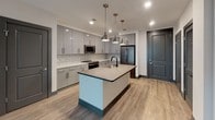 Located at 134 Columbus St in Charleston, SC, this single-floor unit offers a thoughtfully designed layout with contemporary finishes throughout. The open-concept kitchen serves as a central feature, showcasing high-gloss gray cabinetry that extends to the ceiling, a classic white subway tile backsplash, and stainless steel appliances including a range, built-in microwave, and refrigerator. A large center island with a quartz countertop and matte black faucet provides ample workspace and serves as a natural gathering point, illuminated by a trio of industrial-style pendant lights. Light hardwood-style flooring runs throughout the main living areas, complemented by dark baseboards that add a sharp, modern contrast.

The living area benefits from a large multi-pane window that frames views of the surrounding Charleston landscape, paired with a ceiling fan for added comfort. The bedroom presents a clean, minimalist aesthetic with the same warm flooring and a bare pendant fixture. The bathroom features large-format dark gray floor tiles, a gray vanity with white countertop, and direct access to a spacious walk-in closet outfitted with built-in shelving, offering generous and well-organized storage.