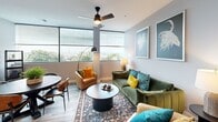 Located at 1230 Elm St in Manchester, NH, this well-designed two-bedroom, one-bathroom apartment offers a thoughtful layout across a single floor. The open-concept living and dining area is a standout feature, bathed in natural light from large windows that frame elevated city views. The living room is anchored by a ceiling fan, light gray walls, and wood-look flooring that flows throughout the unit, lending a cohesive, contemporary feel. The kitchen is sleek and functional, featuring white shaker cabinetry, quartz countertops, stainless steel appliances including a French door refrigerator and dishwasher, and pendant lighting above the breakfast bar. A dedicated dining area with additional window access sits adjacent to the kitchen. The primary bedroom offers a comfortable, carpeted retreat with ample space for furnishings, while the second bedroom mirrors the same clean aesthetic. The full bathroom includes a tub-shower combination with black matte fixtures, a white vanity, and wood-look flooring that ties into the rest of the unit. Throughout the apartment, neutral gray tones provide a versatile backdrop, complemented by recessed and pendant lighting for a polished, modern ambiance.