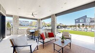 Located at 300 Canvas Ridge Ave in Castle Rock, Colorado, this single-level community amenity space is thoughtfully designed for outdoor living and social gatherings. The centerpiece of the space is a generously sized swimming pool, surrounded by a spacious pool deck lined with lounge chairs — perfect for relaxing under Colorado's abundant sunshine. The pool area is framed by an iron perimeter fence, offering both security and open sightlines to the surrounding residential neighborhood.

Adjacent to the pool, a covered outdoor pavilion serves as the social hub of the community. Anchored by striking stacked-stone columns, the pavilion features a smooth white ceiling equipped with ceiling fans to ensure comfort during warmer months. The space is open on multiple sides, allowing abundant natural light and refreshing breezes to flow through freely. The lounge area is furnished with plush seating accented by bold red pillows, while a separate dining area with a large table and chairs accommodates group gatherings. A built-in gas grill completes the outdoor kitchen setup, making this space ideal for entertaining. Large sliding glass doors connect the pavilion seamlessly to an interior space, further enhancing the indoor-outdoor flow of this well-appointed community retreat.