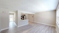 Located at 1932 S Cologne Ave in Mays Landing, NJ, this thoughtfully updated 2-bedroom, 1-bathroom unit offers a clean, modern aesthetic throughout its single-floor layout. The open living area features light wood-style flooring and neutral warm tones, creating a bright and welcoming atmosphere. A half-wall with a breakfast bar connects the living space to the kitchen, which is well-appointed with dark shaker-style cabinetry, white countertops, a subway tile backsplash, and a full suite of stainless steel appliances including a gas range, microwave, dishwasher, and refrigerator. Both bedrooms are carpeted and sized comfortably, with the primary bedroom featuring a wide window that invites natural light and views of the surrounding greenery. Each bedroom is served by a dedicated closet. The full bathroom is finished with tile flooring, white wall tile, a modern vanity with dark hardware, and a mirrored medicine cabinet. A hallway connects the main living areas to the bedrooms and bathroom, with additional utility and storage spaces rounding out the floor plan. Clean white trim and consistent finishes throughout give the unit a cohesive, move-in-ready feel.
