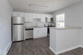 Located at 106 Penner St in Winston-Salem, NC, this single-story home showcases a series of modern updates throughout its layout. The open floor plan, visible in the aerial rendering, connects the main living areas to the kitchen, creating a cohesive and functional flow.

The kitchen is a standout feature, outfitted with crisp white shaker-style cabinetry, light granite-look countertops, and a full suite of stainless steel appliances including a refrigerator, dishwasher, electric range, and microwave. A stainless steel sink with a modern pull-down faucet completes the space, which also benefits from wood-style flooring and baseboard heating.

The bedroom features the same durable wood-style flooring, neutral gray walls, a ceiling fan with light fixture, a textured ceiling, and a window with blinds that allows for natural light. A baseboard heater provides supplemental warmth.

The bathroom is cleanly appointed with a full tub and shower surround, updated fixtures, and matching wood-style flooring. The dedicated laundry room houses a full-size washer and dryer along with a water heater, offering added convenience.

Throughout the home, a consistent neutral color palette and updated finishes contribute to a clean, move-in-ready atmosphere.