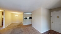 Located at 5300 Woodruff Farm Rd in Columbus, Georgia, this single-floor residence offers a well-organized layout with a clean, neutral aesthetic throughout. The open-concept living and dining areas are finished with warm-toned carpeting and cream-colored walls, creating a bright and welcoming atmosphere. A chandelier anchors the dining space, adding a touch of elegance to the everyday setting. The galley-style kitchen is thoughtfully designed with white cabinetry, granite-look countertops, a double basin sink, and black appliances including a range and refrigerator, all set above durable wood-look flooring. A pass-through window connects the kitchen to the living area, enhancing the sense of openness. The bedrooms are generously sized, each featuring plush carpeting, ceiling fans with integrated lighting, and ample closet space. One bedroom includes a sliding glass door that opens to an outdoor view, bringing in natural light. The bathrooms are well-appointed with tub-shower combinations, white vanity cabinetry, granite-look countertops, and wood-look flooring. Clean white walls and neutral finishes throughout the home create a cohesive and move-in ready environment.