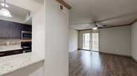 Located at 2401 Repsdorph Dr in Seabrook, TX, this one-bedroom, one-bathroom single-floor residence offers a well-organized layout across a compact yet functional footprint. The living room is a bright, open space featuring rich dark hardwood-style flooring, crown molding, a textured ceiling, and a ceiling fan. A sliding glass door floods the room with natural light and provides direct access to an outdoor area, with vertical blinds offering privacy when desired. The entry foyer, framed by a paneled front door and a nearby window, extends naturally into the living space. The galley-style kitchen is efficiently designed with dark cabinetry, granite countertops, a tile backsplash, and stainless steel appliances including a refrigerator, electric range, microwave, and dishwasher. Light tile flooring keeps the kitchen bright and easy to maintain. The spacious bedroom features plush carpeting, a ceiling fan with light, and a large window with an outdoor view, creating a comfortable and airy retreat. A dedicated closet provides ample storage. The bathroom is finished with granite countertops, dark wood cabinetry, tile flooring, and a shower enclosure. A hallway connects the rooms cohesively throughout the unit.