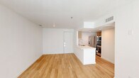 Located at 7880 Alpha Rd in Dallas, TX, this one-bedroom, two-bathroom unit offers a well-designed single-floor layout that maximizes its compact footprint. Light-toned hardwood flooring runs throughout the living areas and bedroom, creating a clean, cohesive aesthetic. The open-concept living, dining, and kitchen area forms the heart of the unit, centered around a white kitchen island with an integrated sink and countertop seating. The kitchen is equipped with warm wood cabinetry, a subway tile backsplash, and stainless steel appliances including a refrigerator and range. A large window in the living area allows ample natural light to fill the space. The bedroom is a comfortable size, featuring a ceiling fan, a large window with exterior views, and direct access to a closet area. The bathrooms include a full bath with a white-tiled tub-shower combo and tile flooring, along with warm wood vanity cabinetry providing storage. Throughout the unit, crisp white walls and clean lines lend a bright, modern feel, while practical touches such as ceiling fans and HVAC vents ensure everyday comfort. The overall ambiance is light, airy, and move-in ready.