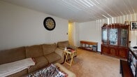 Located at 445 Arion St E in West St. Paul, Minnesota, this single-floor unit offers a practical and functional layout designed for comfortable everyday living. The living room is a welcoming space featuring wall-to-wall carpeting, a textured ceiling, and a large sliding glass door with vertical blinds that allows natural light to fill the room. The open layout accommodates both a seating area and additional living space with ease. The galley-style kitchen is efficiently designed with warm wood cabinetry lining both walls, light-toned countertops, tile flooring, and white appliances including a range and refrigerator. A door at the end of the kitchen provides convenient access. The bedroom is a comfortably sized, carpeted retreat with a textured ceiling and a window dressed with darkening curtains for privacy and restful sleep. The full bathroom features tile flooring, a vanity with a mirrored medicine cabinet, and a shower/tub combination. A hallway connects the main living areas to the bedroom and bathroom, contributing to the unit's straightforward and accessible floor plan. Overall, this space offers a no-frills, functional living environment well-suited for individuals or couples in the West St. Paul community.