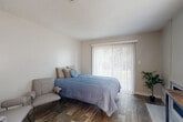 Located along the Cherry Creek Trail in Denver, CO, this efficiently designed one-bedroom, one-bathroom unit makes excellent use of its compact footprint across a single floor. The open layout connects the kitchen and living areas, creating a functional and cohesive living space. The kitchen is outfitted with white shaker cabinets, marble-look countertops, a stainless steel sink with a pull-down faucet, a black refrigerator, a dishwasher, and an electric range with a range hood — offering a clean, modern aesthetic. A peninsula counter connects the kitchen to the main living area, which features hardwood-style flooring throughout and a fireplace, adding warmth and character. Natural light filters in through multiple windows fitted with blinds and vertical shades. The bedroom is generously sized relative to the overall floor plan and includes a sliding glass door that opens to the outdoors, allowing for ample natural light and ventilation. A dedicated closet provides convenient storage. The bathroom features a white vanity with marble-look countertops, a large mirror, and modern fixtures, all finished with the same cohesive, contemporary styling found throughout the home. The textured ceilings and neutral color palette give the space a clean, move-in-ready appeal.