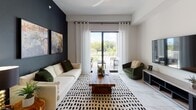 This single-story residence at AMLI Plantation offers a thoughtfully designed open-concept layout across two bedrooms and two bathrooms. The living area makes a bold statement with a dramatic dark accent wall serving as a backdrop for curated artwork, while sheer floor-to-ceiling curtains frame sliding glass doors that lead to a private balcony overlooking lush greenery. Marble-look tile flooring flows throughout the main living spaces, lending a polished, cohesive aesthetic.

The kitchen is a standout feature, outfitted with matte dark cabinetry extending to the ceiling, stainless steel appliances, a decorative mosaic tile backsplash, and crisp white countertops. A generously sized island with pendant lighting and bar seating anchors the space, seamlessly connecting to a dedicated dining area.

Both bedrooms are well-proportioned and filled with natural light from large windows. The primary bedroom includes a walk-in closet and marble-look tile flooring, while the second bedroom features neutral tones and outdoor views. Each bathroom is cleanly finished with light wood-look flooring, a dark floating vanity, and bright, open layouts that maintain the home's contemporary character throughout.