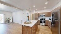 Located at 61 W 400 S in Provo, Utah, this well-designed two-bedroom, two-bathroom residence offers a clean, modern aesthetic throughout its single-floor layout. The open-concept living and kitchen area serves as the heart of the home, featuring light hardwood-style flooring, recessed lighting, and crisp white walls that create a bright, airy atmosphere. The kitchen is equipped with warm wood-toned cabinetry, a white subway tile backsplash, stainless steel appliances including a refrigerator, range, microwave, and dishwasher, and a generously sized center island with a white countertop — ideal for both meal preparation and casual dining. The living area flows naturally from the kitchen and includes access to a private balcony with vertical blinds, allowing for abundant natural light. Both bedrooms are carpeted and feature neutral tones, with windows providing natural light and a calm, restful environment. The primary bedroom includes a dedicated en-suite bathroom with a walk-in glass shower, a wood-vanity with white countertop, and access to a walk-in closet. The second bathroom offers a full tub-shower combo with the same consistent wood-and-white finishes. Throughout the space, the design maintains a cohesive, contemporary style with clean lines and quality finishes.