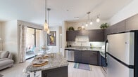Located in Gilbert, Arizona, this well-appointed 2-bedroom, 2-bathroom residence offers a thoughtfully designed single-level layout with modern finishes throughout. The open-concept kitchen is a standout feature, showcasing dark espresso cabinetry, granite countertops, stainless steel appliances, a large central island with bar seating, and pendant lighting — ideal for both everyday cooking and entertaining. Light wood-style flooring flows seamlessly through the kitchen and into the adjoining living area, which features a ceiling fan, a bold accent wall, and a sliding glass door that invites natural light. The generously sized primary bedroom offers plush carpeting, a ceiling fan, and sliding glass door access to an outdoor area with outdoor views. The second bedroom is bright and versatile with carpeted flooring and ample wall space. Both bathrooms are finished with dark vanity cabinetry, granite-style countertops, large mirrors, and tile-style flooring. A dedicated in-unit laundry room houses a full-size washer and dryer alongside shelving for added storage. Two closets provide additional organization throughout the home, completing this well-rounded and stylish residence.