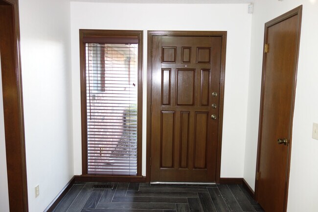 Dentro de la entrada principal. Persianas de madera en la ventana de entrada y un gran armario para abrigos a la derecha. - 3324 E 73rd St