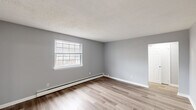 This efficiently designed 2-bedroom, 1-bathroom single-floor unit offers a practical and comfortable layout. Neutral grey walls and white trim are consistent throughout, creating a clean and cohesive aesthetic. Light-toned luxury vinyl plank flooring runs through the main living areas, kitchen, and primary bedroom, while the second bedroom features plush carpeting underfoot.

The kitchen is equipped with dark espresso cabinetry, light countertops, and white appliances including a coil-top range, built-in microwave, and refrigerator. A ceiling fan with integrated lighting adds both function and airflow. The adjacent dining or living area shares this open feel, with its own ceiling fan and a window that invites natural light.

The spacious primary bedroom benefits from a large window with exterior views and a baseboard heating system, while the second bedroom also features a ceiling fan, carpeted flooring, and a closet. Both rooms are finished with the same neutral grey palette.

The bathroom is outfitted with white tile surrounding the bathtub and shower area, tile flooring, and a window that provides natural ventilation. A hallway connects all rooms, contributing to the unit's functional flow. Textured ceilings and baseboard heaters are found throughout the space.