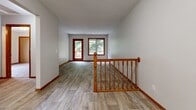 This two-floor home is designed with practical functionality in mind, featuring warm wood accents, including rich oak-toned trim and baseboards, that carry consistently throughout both levels. The upper floor centers around a bright, open living area with light-toned luxury vinyl plank flooring and wood-framed windows and a door providing direct access to an outdoor deck, filling the space with natural light and views of surrounding greenery. A kitchen on this level features rich wood cabinetry with brass hardware, light countertops, a peninsula with a raised breakfast bar, and black appliances including a range, microwave, and refrigerator. Additional rooms on this floor include a carpeted bedroom with dual closets and a separate room with wood-look flooring.

The lower level expands the living space considerably, offering a large carpeted open area with a textured ceiling and a dedicated laundry area equipped with a full-size washer and dryer. A second kitchen on this floor mirrors the upper level with extensive wood cabinetry, generous counter space, and a dishwasher. A sliding glass door on this level provides access to the backyard with outdoor views. Throughout both floors, neutral wall tones and consistent wood trim create a cohesive, understated aesthetic.